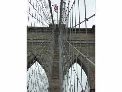 Drapeau américain situé en haut du pilier ouest du Pont de Brooklyn qui flotte au vent 
