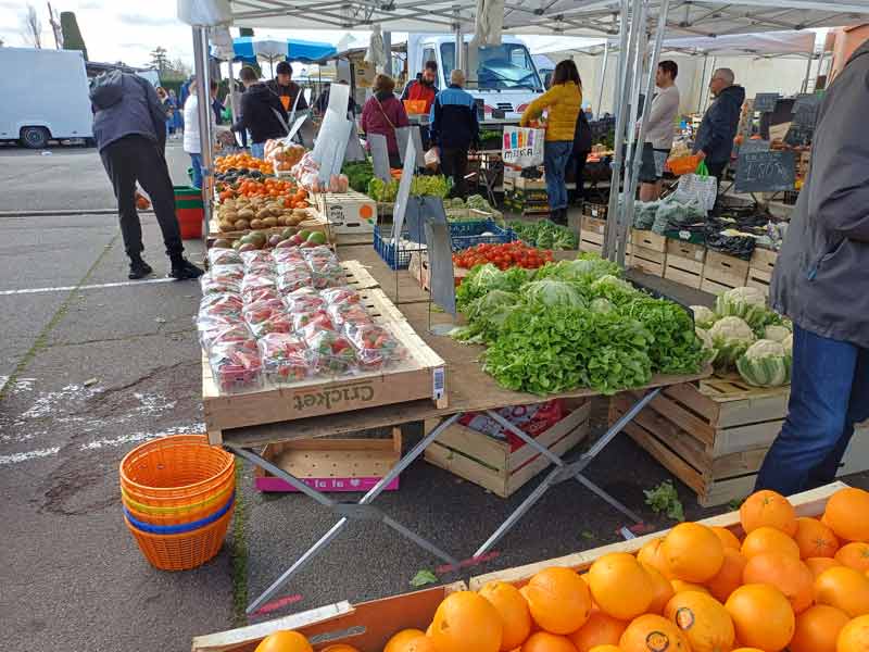 Étal de fruits et légumes frais sur un marché en plein air, salades, tomates et fraises en avant-plan