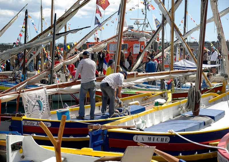 Marins en tenue rayée préparant leurs barques traditionnelles colorées lors d’une fête nautique à Sète