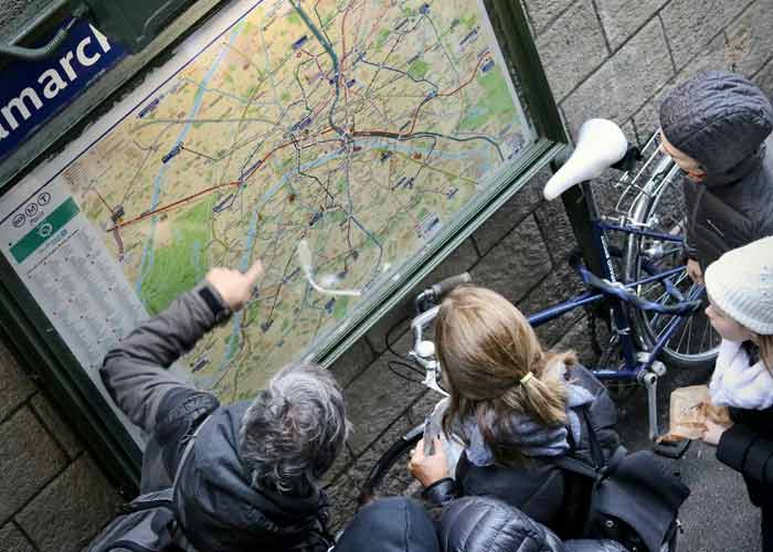 Touristes consultant un plan de Paris pour organiser une visite de Paris, avec vélos et carte des transports