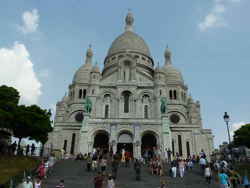 Façade de la basilique du Sacré-Cœur à Montmartre, avec les escaliers et les visiteurs sur le parvis