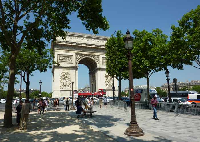 Arc de Triomphe � Paris vu depuis une all�e arbor�e, avec des visiteurs et l�animation de la place en arri�re-plan