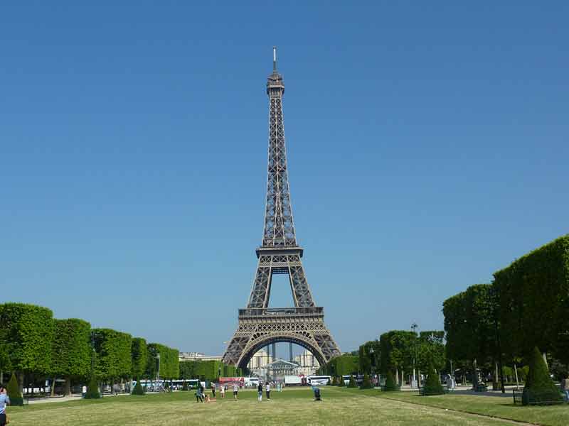 La tour Eiffel vue depuis le Champ-de-Mars sous un ciel bleu, première étape incontournable pour visiter Paris avec des enfants