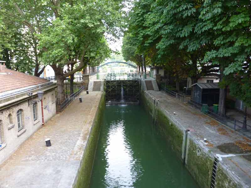 Écluse du canal Saint-Martin bordée d’arbres et de passerelles, une balade insolite à Paris pour les enfants fascinés par les bateaux