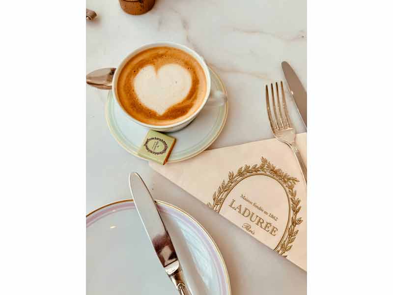 Café latte au cœur dessiné servi chez Ladurée Paris sur une table élégante