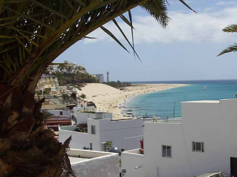 Plage de Morro Jable à Fuerteventura avec ses maisons blanches, palmiers et le phare en arrière-plan