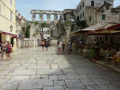 Promeneurs et terrasses animées devant la Porte d’Argent dans le palais de Dioclétien à 
												Split, en Croatie, entre vieilles pierres romaines et ruelles pavées