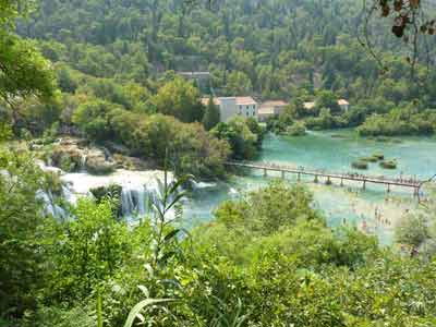 Vue sur les cascades, passerelle en bois et baigneurs dans le parc national de Krka