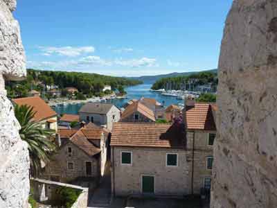 Vue plongeante sur les toits en tuiles et le port de Hvar, encadrée par les murs en pierre d'une forteresse, 
												avec la mer Adriatique en toile de fond, en Croatie