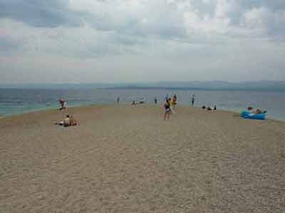Plage de galets de Zlatni Rat en Croatie lors d'un road-trip croate, avec des vacanciers profitant *
												de la mer Adriatique sous un ciel nuageux