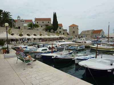 Port pittoresque de Bol sur l'île de Brač vu lors d'un road trip en Croatie, avec ses petits bateaux amarrés, 
												ses maisons en pierre et ses terrasses en bord de quai