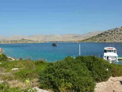 Bateaux amarrés dans les eaux turquoise du parc national des Kornati en Croatie, entourés de collines arides 
												et de végétation méditerranéenne