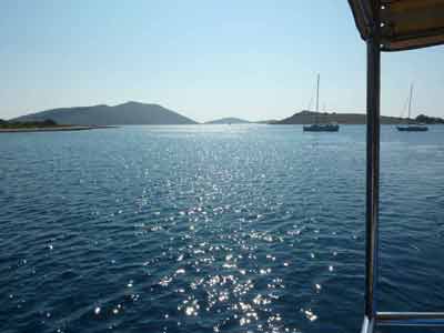 Reflets du soleil sur la mer Adriatique dans le parc national des Kornati en Croatie, avec des voiliers au mouillage 
												et des îles à l’horizon