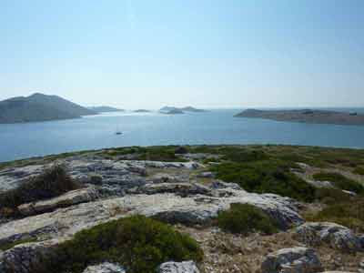 Vue panoramique sur les îles du parc national des Kornati en Croatie depuis un promontoire rocheux, avec un voilier 
												solitaire sur l’eau scintillante