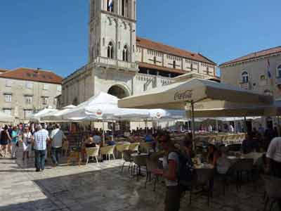 Terrasse de café animée sur une place ensoleillée devant la cathédrale de Trogir