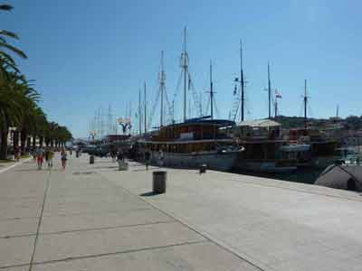 Promenade en bord de mer bordée de palmiers et de bateaux amarrés à Trogir lors d'un road trip en Croatie