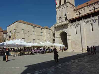 Terrasse de café sur une place ensoleillée de Trogir en Croatie, devant l’entrée de la cathédrale Saint-Laurent