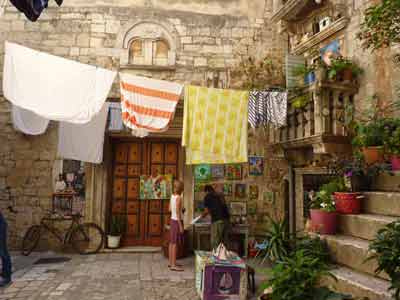 Cour pittoresque avec linge étendu, plantes en pots et étal d’artisanat à Trogir