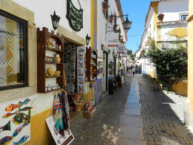 Ruelle pavée bordée de boutiques artisanales à Óbidos, village médiéval du Portugal