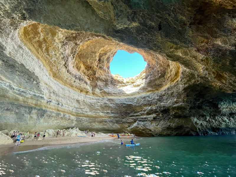 Intérieur de la grotte de Benagil au Portugal avec visiteurs en kayak sous l’ouverture naturelle