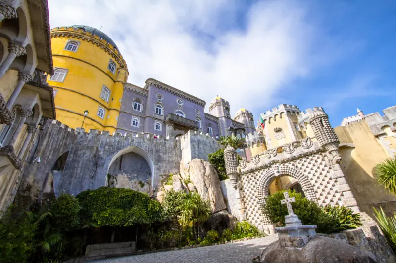 Entrée et façades colorées du Palais national de Pena à Sintra, avec ses murs jaunes et violets sous un ciel bleu