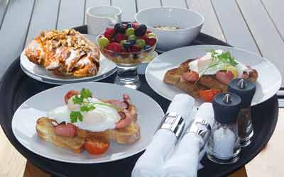 Petit-déjeuner suédois avec des fruits, des œufs, du bacon, des tomates et du pain