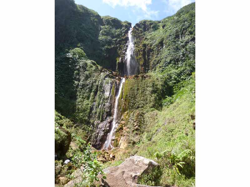 Magnifique cascade des chutes du Carbet en Guadeloupe, tombant le long de falaises verdoyantes couvertes de végétation tropicale, sous un ciel dégagé