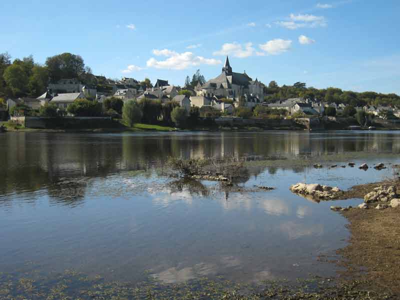 Vue du village de Candes-Saint-Martin en bord de Loire, avec son église imposante et ses maisons en pierre se reflétant dans 
								les eaux calmes du fleuve