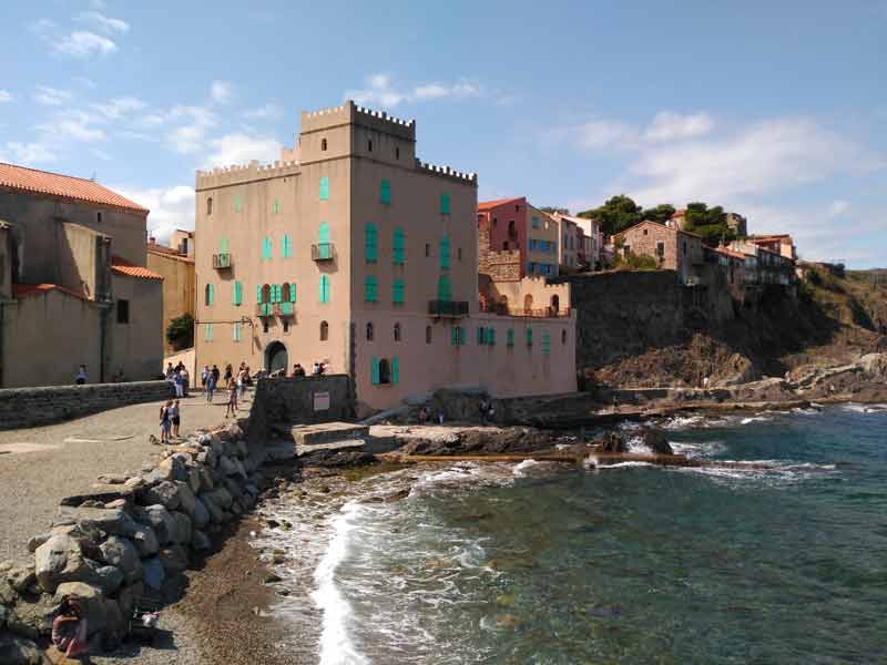 Vue du château royal de Collioure en bord de mer, avec les façades colorées du village et la Méditerranée