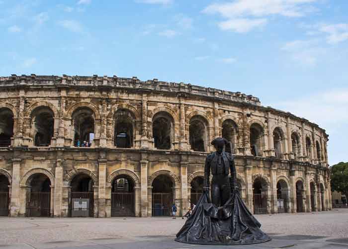 Vue des ar�nes de N�mes avec au premier plan la statue en bronze d�un matador en tenue de torero