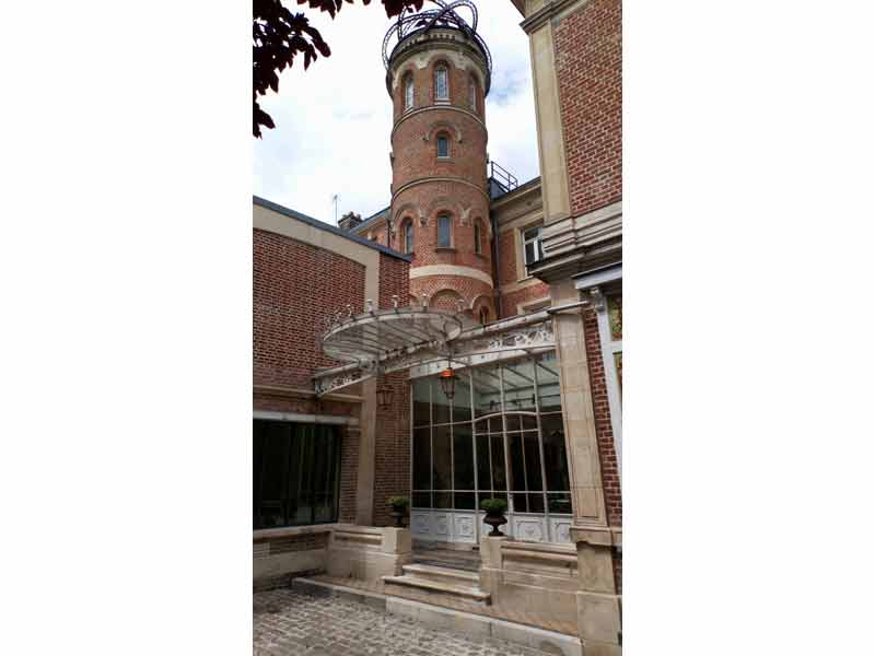 Maison de Jules Verne à Amiens, bâtiment en briques rouges avec une verrière élégante et une tour d'observation, lieu emblématique où l'écrivain a vécu et imaginé ses célèbres voyages extraordinaires