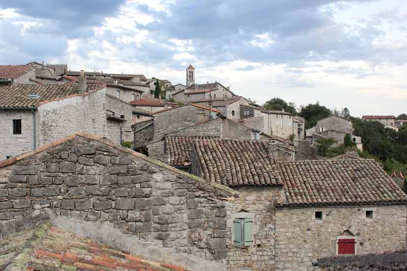 Toits en tuiles et maisons en pierre du village médiéval de Balazuc en Ardèche, sous un ciel nuageux