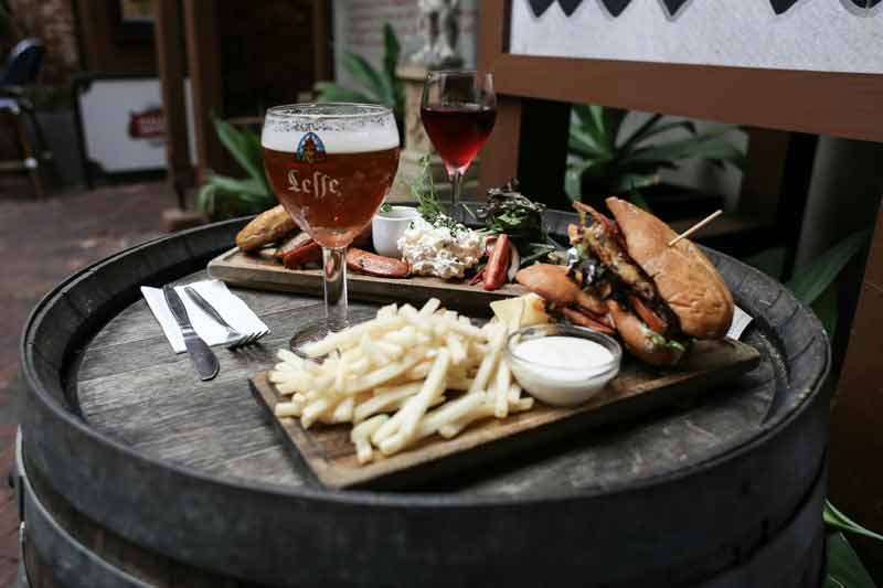 Planche gourmande avec frites, burger et bière belge Leffe dégustée en terrasse lors d’un week-end d’été à Bruxelles