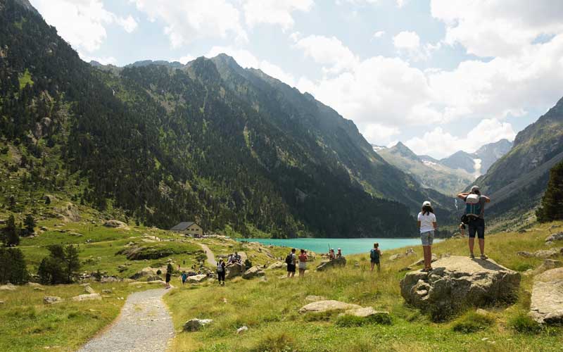 Randonneurs admirant les eaux turquoise du lac de Gaube près de Cauterets, avec le Vignemale en fond de vallée
