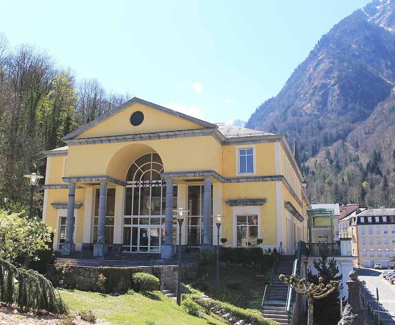Façade jaune à colonnes des thermes de César à Cauterets, au pied des montagnes de la vallée