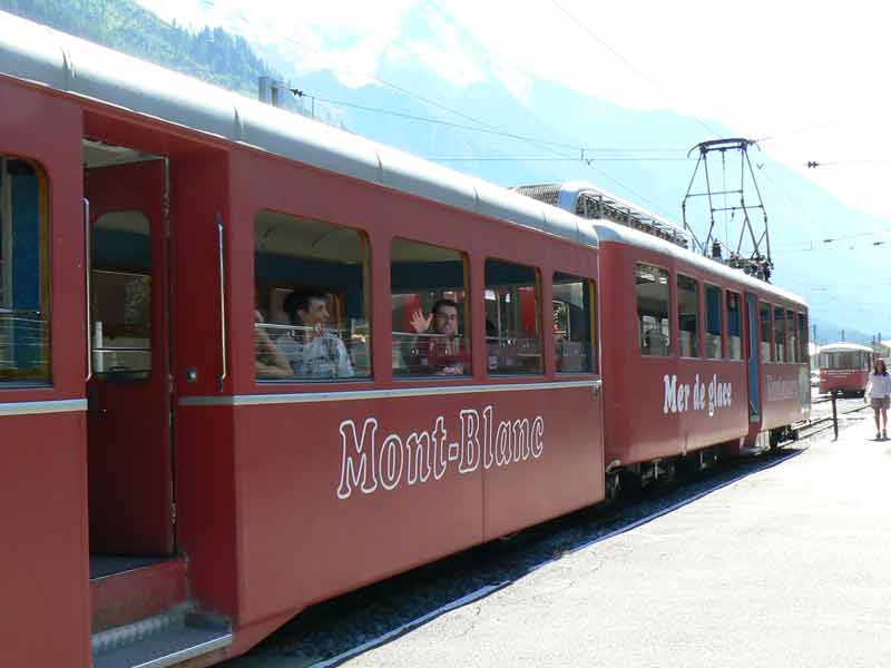 Train rouge à crémaillère du Montenvers partant de Chamonix en direction de la Mer de Glace, avec le massif du Mont-Blanc en arrière-plan