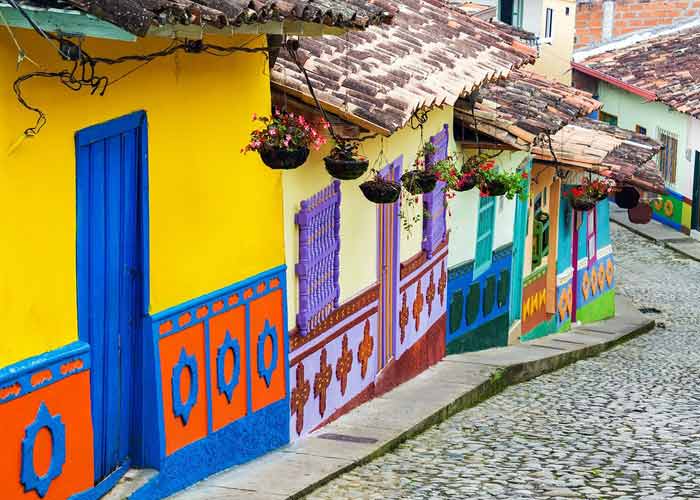 Ruelle pittoresque en Colombie avec des maisons colorées ornées de motifs géométriques et des jardinières fleuries, typiques de l'architecture locale