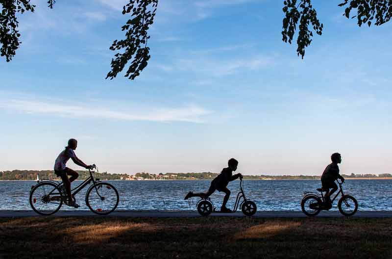 Famille qui fait un tour de vélo sur une piste cyclable autour du lac de Hourtin