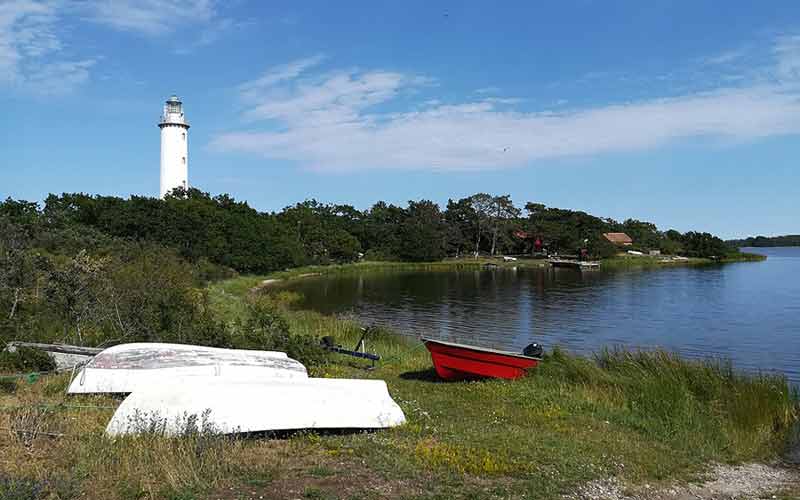 Barques sur l'herbe au bord de la mer Baltique avec vue sur le phare de Långe Erik