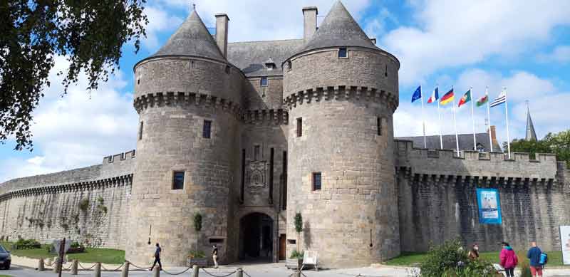 Entrée fortifiée de la cité médiévale de Guérande avec ses deux tours en pierre et les drapeaux européens flottant au vent