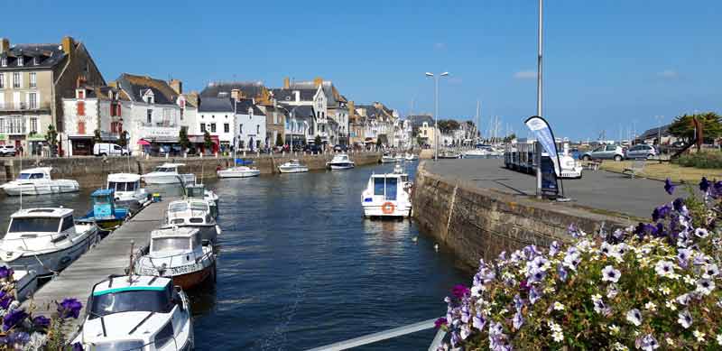 Port du Croisic animé sous un ciel bleu, avec ses bateaux amarrés et ses maisons de caractère en bord de quai