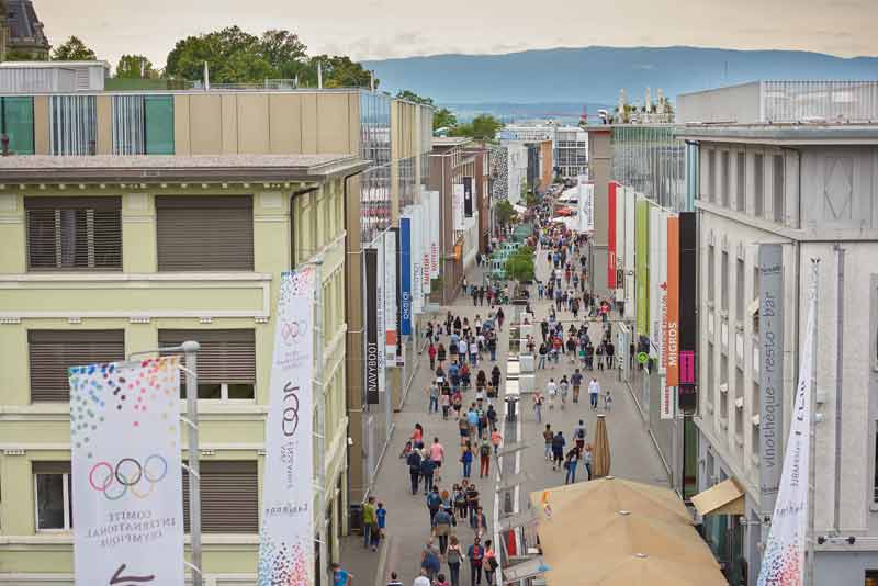 Vue animée du quartier du Flon à Lausanne, avec ses bâtiments modernes, ses commerces et de nombreux passants dans la rue piétonne