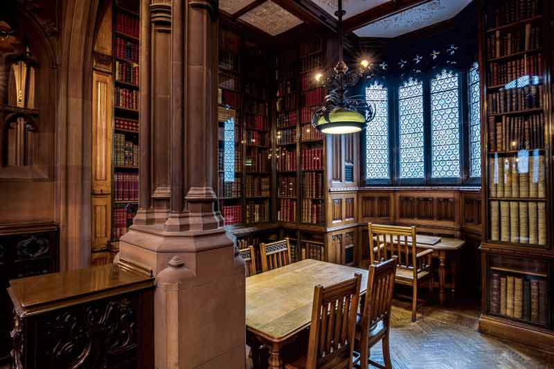 Intérieur de la John Rylands Library à Manchester avec boiseries et étagères de livres anciens