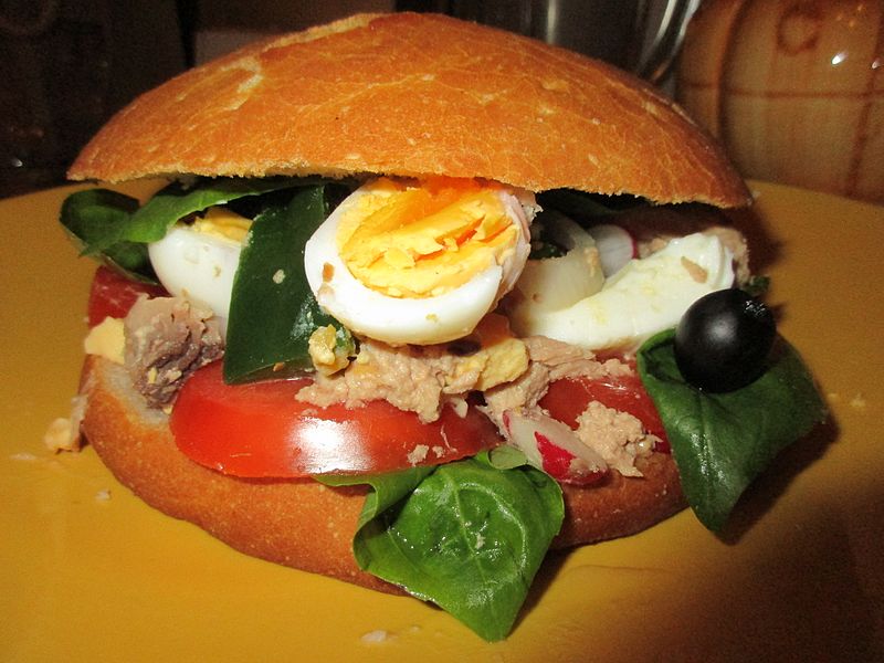 pan-bagnat : petit pain rond fendu en deux avec des tomates, des oignons, des poivrons, des olives noires et des anchois