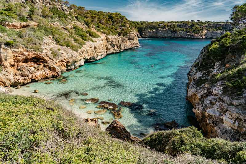 Vue paradisiaque de la plage de Caló des Moro avec ses eaux turquoise et ses falaises rocheuses, un lieu à ne pas manquer pour visiter Palma de
Majorque et ses alentours
