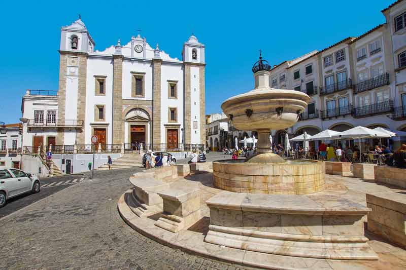 Fontaine de marbre et église de Santo Antão sur la place centrale d’Évora, en Alentejo