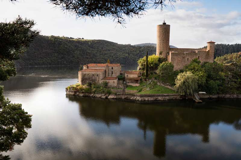 Île de Grangent et son château médiéval se reflétant dans le lac de Grangent, au cœur des gorges de la Loire