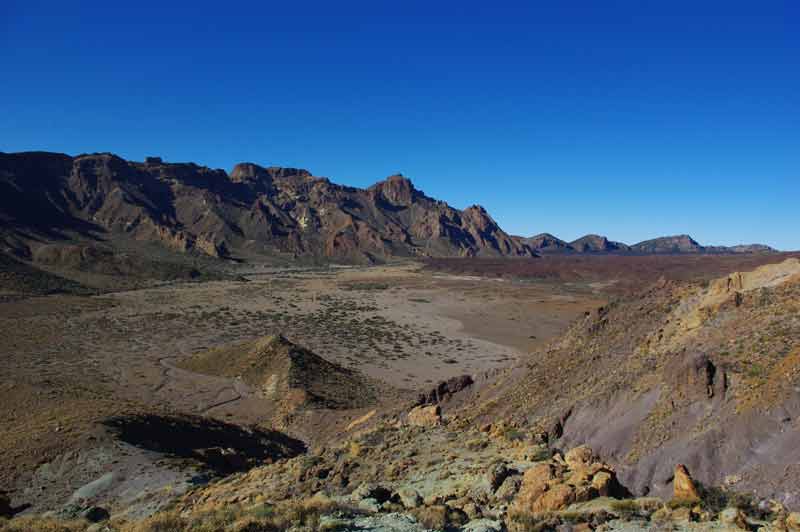 Paysage lunaire du parc national du Teide à Tenerife, avec ses roches volcaniques ocre et la caldeira de Las Cañadas sous un ciel bleu