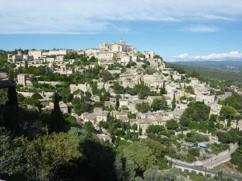 Vue panoramique sur le village perché de Gordes et ses maisons en pierre dans le Luberon, entouré de verdure et collines