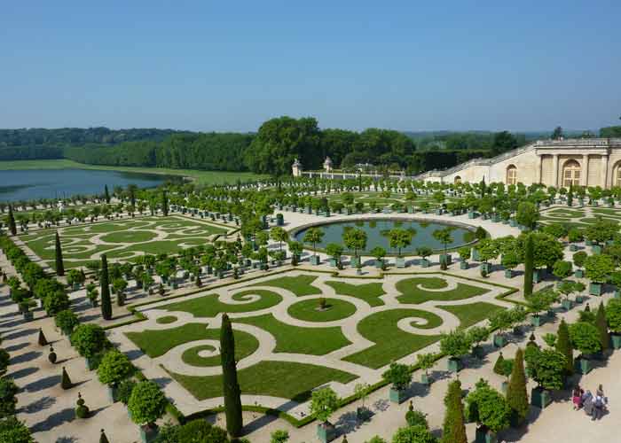 Jardins à la française du château de Versailles
avec parterres géométriques, fontaines et verdure luxuriante sous un ciel bleu